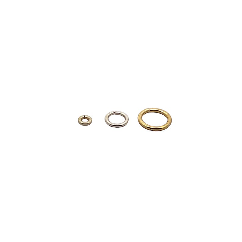 May include: Three jump rings in different sizes. The smallest ring is silver, the middle ring is silver, and the largest ring is gold.