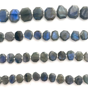 以下が含まれることがあります： グレーとブルーのシェードのファセットカットされたラブラドライトジェムストーンビーズのストランド。ビーズは白い糸に糸に通され、4列に配置されています。