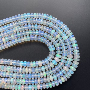 May include: A strand of white opal beads with iridescent colors. The beads are faceted and have a slightly oval shape.