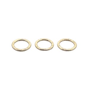 May include: Three gold-colored metal jump rings. The rings are smooth and have a slightly textured surface.