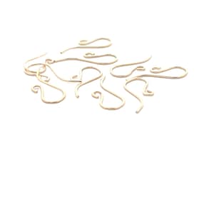 May include: A collection of gold-colored earring hooks, scattered against a white background. The hooks have a simple, curved design with a looped end for attaching to the ear and a hook for securing the earring.