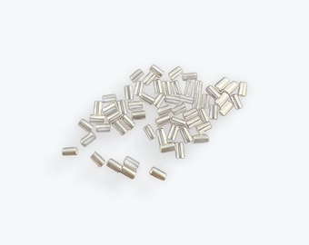 May include: A pile of silver-colored metal rivets, scattered on a white background.