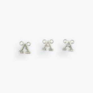 May include: Three silver letter A charms with two jump rings on each charm.