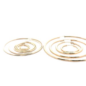 May include: Set of five gold hoop earrings of varying sizes. The earrings are arranged in two groups, with the larger hoops on the right and the smaller hoops on the left.