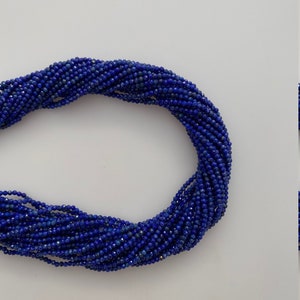 以下が含まれることがあります： 濃い青色のラピスラズリジェムストーンビーズのストランド。ビーズはファセットカットされており、わずかに不規則な形をしています。ビーズは透明な糸に糸で通されています。