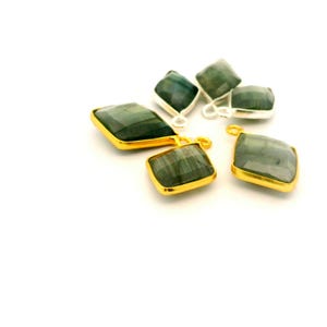 May include: Six gemstone pendants with a faceted, emerald-green appearance. The pendants have a square shape with rounded corners. Some are set in gold-colored metal, while others are in silver-colored metal. Each pendant has a small loop for attaching to a chain.
