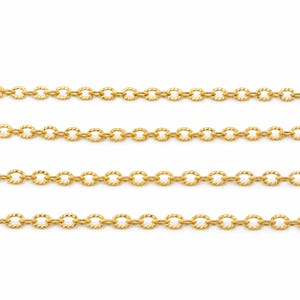 May include: A gold-toned metal chain featuring a series of interconnected oval links. Each individual link has a textured, faceted surface that reflects light, creating a repeating pattern across the four horizontal rows of the chain shown.