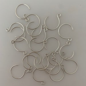 Pode incluir: Um monte de argolas de salto prateadas, um tipo de descoberta de joias usado para conectar componentes de joias.