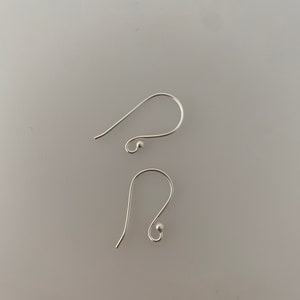 May include: Two silver earring hooks with a small ball at the end of each hook.