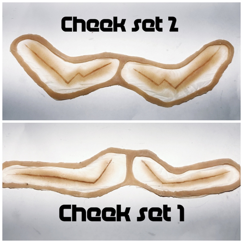 May include: Two sets of brown cheek prosthetics. The top set is labeled "Cheek set 2" and the bottom set is labeled "Cheek set 1".