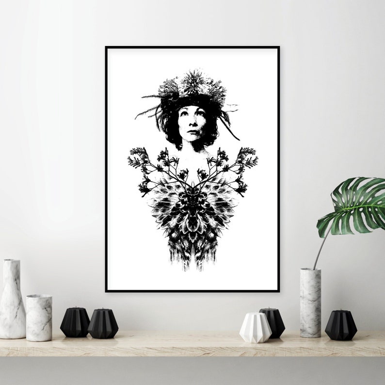May include: Monochrome art print depicting a woman adorned with a floral headdress and a decorative floral design. The artwork is framed in a black frame and displayed on a white wall. The print has a vintage or botanical theme.