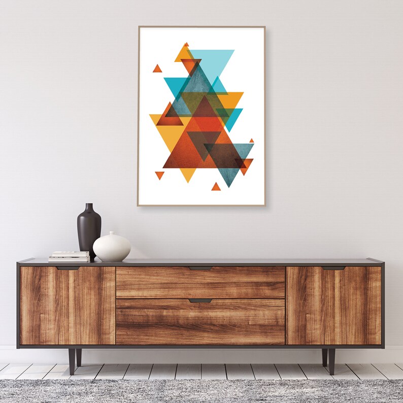 K&ouml;nnte beinhalten: Abstrakter geometrischer Kunstdruck mit einer Komposition aus &uuml;berlappenden Dreiecken in Orange-, Gelb-, Blau- und Braunt&ouml;nen. Der Druck ist gerahmt und an einer Wand &uuml;ber einer Kommode aus Holz angebracht.