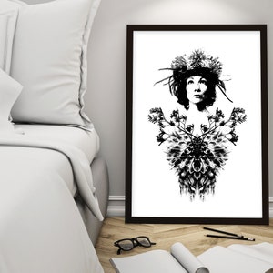 May include: Monochrome art print depicting a woman adorned with a floral headdress and a detailed floral design on the chest. The artwork is framed in a dark brown frame and set against a white backdrop. The print is on a wooden floor.