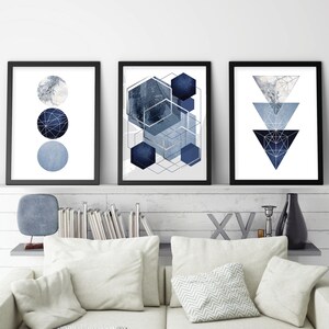 May include: Three framed abstract geometric prints with a blue and silver color scheme. The prints feature circles, hexagons, and triangles.