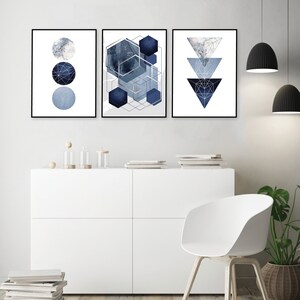 May include: Three abstract geometric wall art prints in shades of blue and gray. The prints feature a circle, a hexagon, and a triangle.