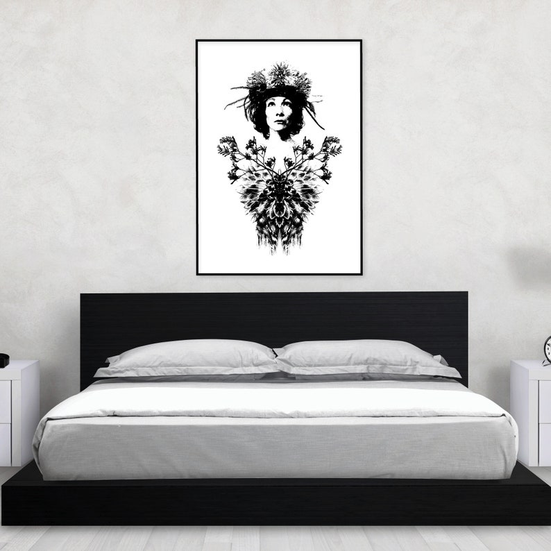 May include: Monochrome art print featuring a woman adorned with a floral crown and a decorative floral pattern. The framed artwork hangs above a black bed frame with white bedding. The room has white walls and a white bedside table.