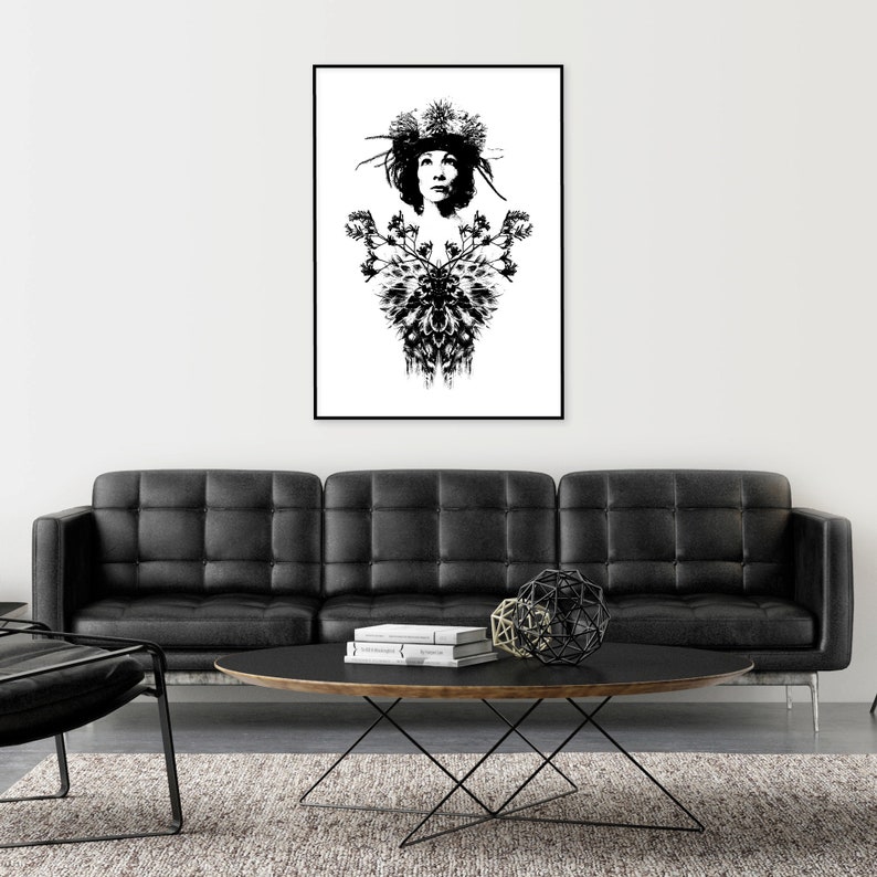 May include: Monochrome art print depicting a woman adorned with a floral crown and a decorative floral design. The artwork is framed in black and hangs above a black leather sofa. The print is a striking piece.