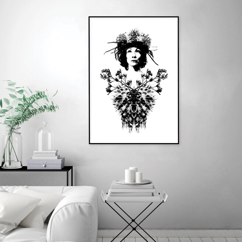 May include: Monochrome art print depicting a woman adorned with a floral headdress and a decorative floral design. The artwork is framed in black and displayed on a white wall.