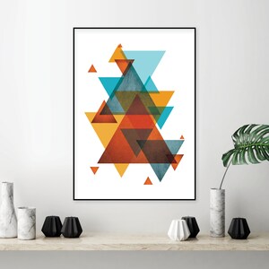 K&ouml;nnte beinhalten: Abstrakter geometrischer Kunstdruck mit einem mehrschichtigen Design aus &uuml;berlappenden Dreiecken in Orange-, Gelb-, Blau- und Braunt&ouml;nen. Der Druck ist in einem schwarzen Rahmen gerahmt und an einer wei&szlig;en Wand ausgestellt.