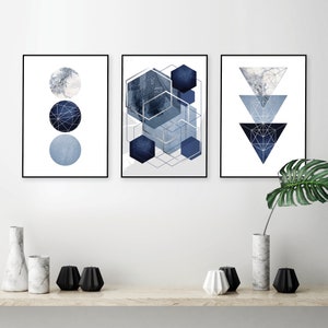 May include: Three framed prints with geometric shapes in shades of blue and silver. The left print features three circles, the middle print features overlapping hexagons, and the right print features three triangles.