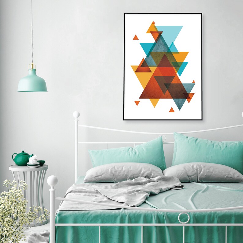 K&ouml;nnte beinhalten: Abstrakter geometrischer Kunstdruck mit &uuml;berlappenden Dreiecken in Orange-, Gelb-, Blau- und Braunt&ouml;nen. Der Druck ist in einem schwarzen Rahmen gerahmt und h&auml;ngt an einer wei&szlig;en Wand &uuml;ber einem Bett mit t&uuml;rkisfarbener Bettw&auml;sche.