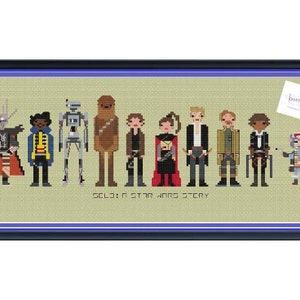 Pode incluir: Obra de arte em ponto cruz com personagens de "Solo: A Star Wars Story". A peça emoldurada mostra figuras pixeladas, incluindo um Wookiee e robôs. O fundo é bege claro e a moldura é azul escuro. O texto "SOLO: A STAR WARS STORY" é visível.
