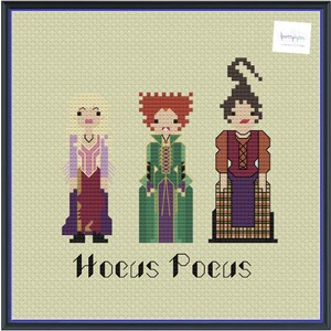 Pode incluir: Padrão de ponto cruz com três figuras estilizadas do filme "Hocus Pocus". As figuras estão em um estilo pixelizado, com o título do filme abaixo. O fundo é bege claro e a imagem é emoldurada por uma borda azul escura.