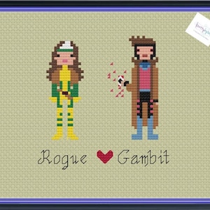 May include: Cross-stitch pattern featuring Rogue and Gambit from the X-Men comics. The pattern shows Rogue in her green and yellow costume and Gambit in his brown and pink costume. The text "Rogue ♥ Gambit" is below the characters.