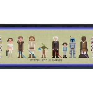 Pode incluir: Uma bordada em ponto cruz, emoldurada, com personagens de "Star Wars: Ataque dos Clones". A obra apresenta figuras pixeladas de personagens icónicos como Stormtroopers, Yoda e Boba Fett, num fundo verde claro. O título está bordado na parte inferior.