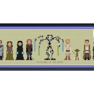 Op de afbeelding: Een ingelijst kruissteekkunstwerk met personages uit "Star Wars: Revenge of the Sith". Het stuk toont gepixelde figuren van Anakin, Padme, Obi-Wan en anderen, met de titeltekst eronder. De lijst is donkerblauw.