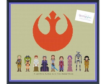 Peut inclure: Motif de point de croix représentant le symbole de l'Alliance Rebelle de Star Wars, avec une ligne de personnages féminins de la franchise en dessous, dont la Princesse Leia, Ahsoka Tano et Sabine Wren. Le texte en dessous indique "La place d'une femme est dans la Résistance."