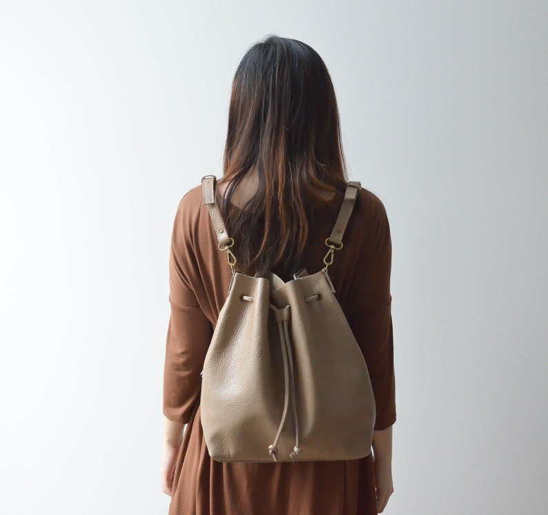 Backpack view of convertible leather bucket bag in sand/tan color.