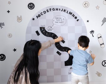May include: A wall decal set featuring a road map design with the alphabet and various black and white graphics. The set includes a road, car, and speech bubble with the text "help me build a road home!".
