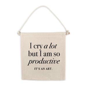 May include: A white canvas banner with black text that reads "I cry a lot but I am so productive. It's an art."