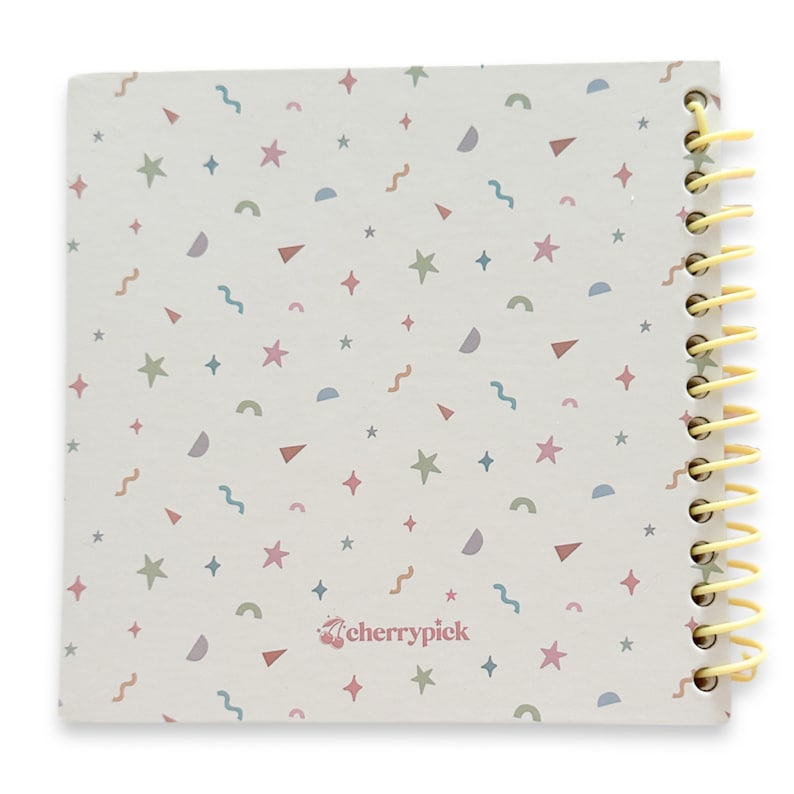 Puede incluir: Una libreta de espiral blanca con un patr&oacute;n de confeti colorido y el texto "cherrypick" en la portada.
