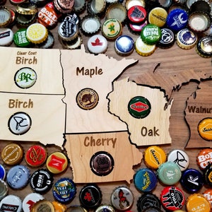 May include: A wooden map of the state of Wisconsin with different wood types labeled for each region. The map is surrounded by bottle caps of various colors and designs.