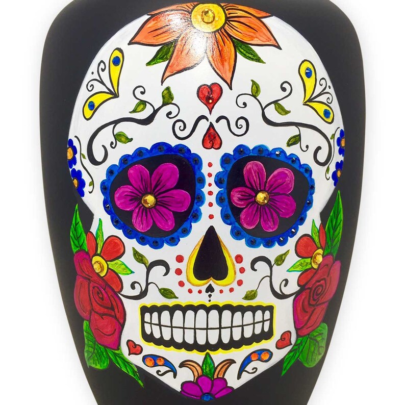 Multi-colored flowers and authentic crystals embellish a white sugar skull on the front of this adult-sized metal urn painted all-over black.