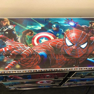 May include: A multi-drawer dresser with a colorful comic book design featuring Spiderman, Thor, Iron Man, and Captain America. The drawers are decorated with images of the characters and the American flag.