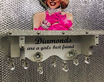 May include: A white shelf with the text "Diamonds are a girls best friend" and a crystal-like design. The shelf has a cutout of Marilyn Monroe in a pink dress. The shelf has crystal-like drops hanging from it.
