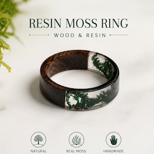 May include: A ring featuring a dark brown wood segment and a clear resin segment containing green moss. Text reads: RESIN MOSS RING, WOOD & RESIN, NATURAL WOOD, REAL MOSS IN RESIN, HANDMADE UNIQUE, RING SIZE: 10. The band has a smooth, polished finish.
