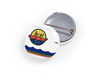May include: A white button with a colorful image of a canoe with three people paddling in it. The canoe is in a blue circle with a yellow sun behind it. The bottom of the button has a blue, green, and red stripe.