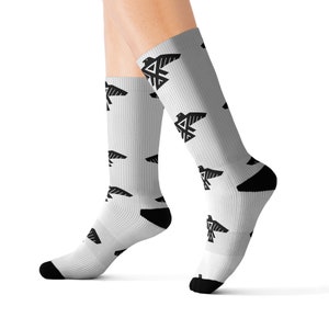 Puede incluir: Calcetines blancos con un patrón de pájaro geométrico negro. Los calcetines se muestran en las piernas de una modelo.