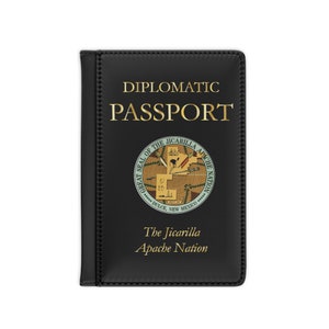 May include: Black passport cover with gold lettering that reads "DIPLOMATIC PASSPORT". The cover features a circular emblem and the text "The Jicarilla Apache Nation".
