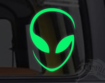 May include: Green alien head silhouette decal sticker on a car window. The sticker is a simple outline of an alien head with large eyes and a small mouth.