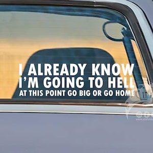 Può includere: Un adesivo bianco su un finestrino di un'auto con la scritta "I ALREADY KNOW I'M GOING TO HELL AT THIS POINT GO BIG OR GO HOME." L'auto è grigio chiaro con un fanale posteriore rosso e uno specchietto laterale.