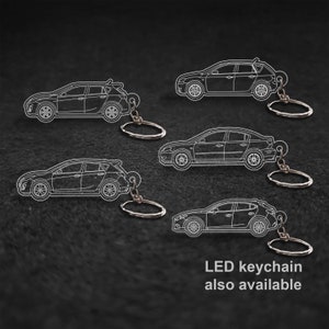May include: Four silver car keychains with a white outline of a car on each. The keychains are on a black background. The text "LED keychain also available" is at the bottom of the image.