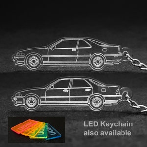 以下が含まれることがあります： 車の側面の輪郭が描かれた透明なアクリル製のキーホルダー。キーホルダーは銀色のチェーンに繋がっています。画像には、「NEON」と印刷されたカラフルなアクリル製のキーホルダーのアップも写っています。「LEDキーホルダーも販売中」というテキストが画像の下に印刷されています。