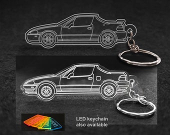 May include: A white outline of a Honda CRX car on a black acrylic keychain. The keychain has a silver metal ring and chain. The text "LED keychain also available" is printed below the car.