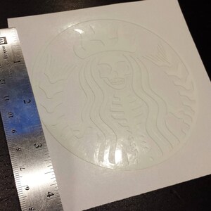 May include: White sticker with a skeleton mermaid design, similar to the Starbucks logo. The sticker is on a white background.