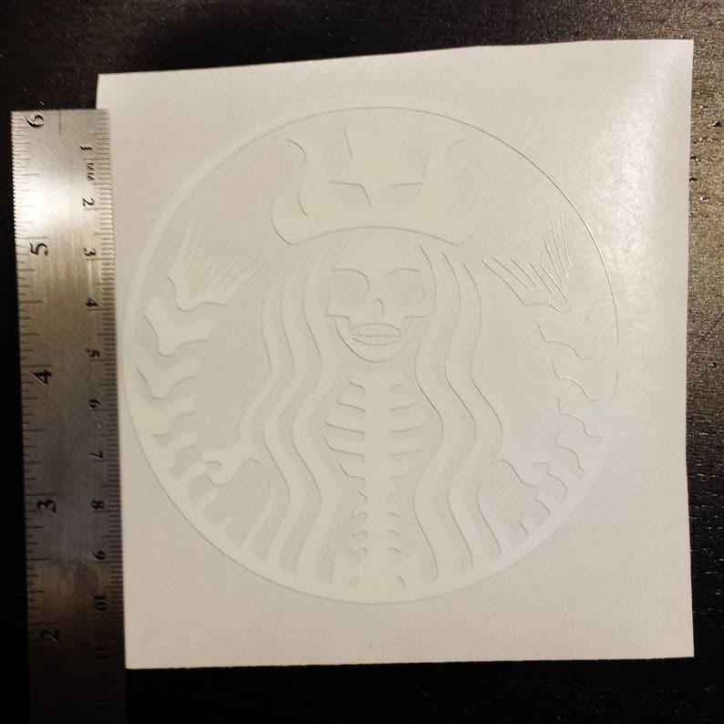 May include: White sticker with a raised design of a skeleton mermaid with long hair and a crown. The mermaid is holding a cup in each hand.